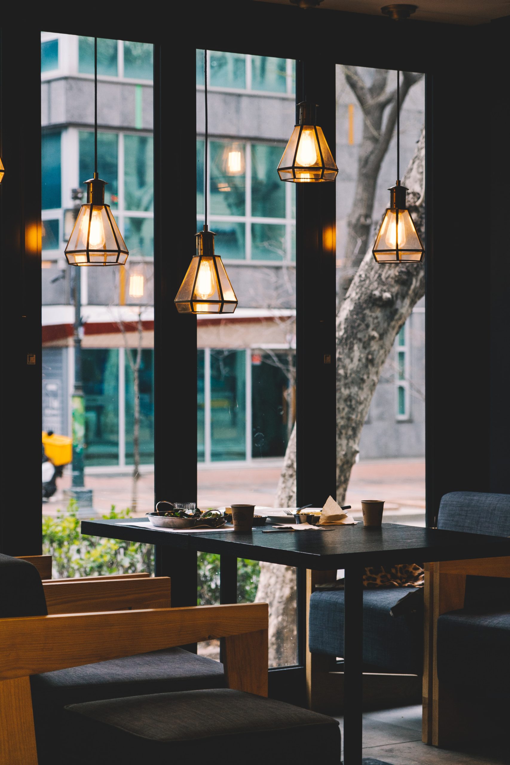 tavolo e sedie da pranzo sotto quattro lampade a sospensione illuminate