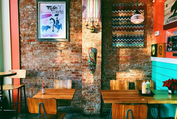 two square brown wooden dining tables near brown brick wall